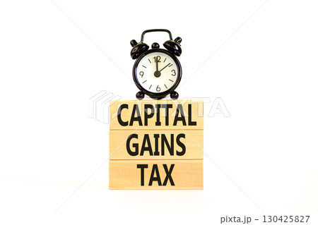 Capital gains tax symbol. Concept words Capital gains tax on beautiful wooden block. Black alarm clock. Beautiful white background. Business and capital gains tax concept. Copy space. Capital gains tax symbol. Concept words Capital gains tax on beautiful wooden block. Black alarm clock. Beautiful white background. Business and capital gains tax concept. Copy space. 130425827