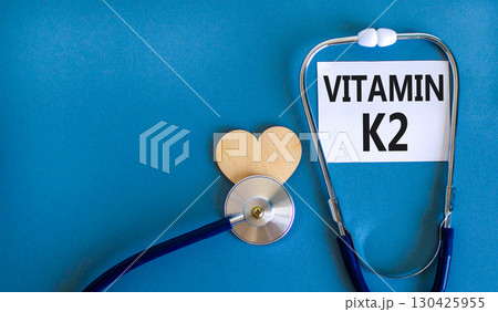 Vitamin K2 phylloquinone symbol. Concept words Vitamin K2 on beautiful white card. Wooden heart and stethoscope. Beautiful blue background. Medical healthy lifestyle Vitamin K2 phylloquinone concept. Vitamin K2 phylloquinone symbol. Concept words Vitamin K2 on beautiful white card. Wooden heart and stethoscope. Beautiful blue background. Medical healthy lifestyle Vitamin K2 phylloquinone concept. 130425955