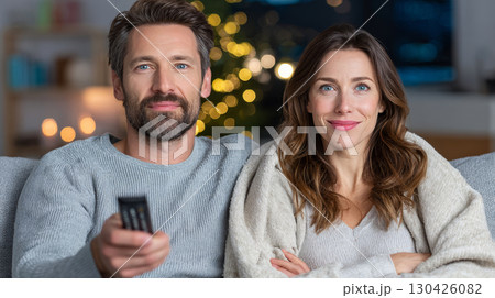 Happy couple sitting on a couch watching television at home during a cozy winter evening 130426082