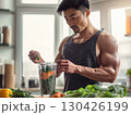 Muscular man preparing vegetable smoothie with fresh greens in bright kitchen showing healthy fitness lifestyle 130426199