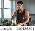 Fit man preparing healthy spinach and berry smoothie in kitchen with natural morning light and clean diet ingredients 130426201