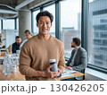Smiling young man holding vitamin bottle in modern office promoting healthy habits and wellness lifestyle 130426205