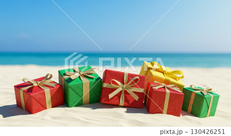 Colorful Christmas gifts on a sandy tropical beach with the ocean and blue sky in the background.  130426251