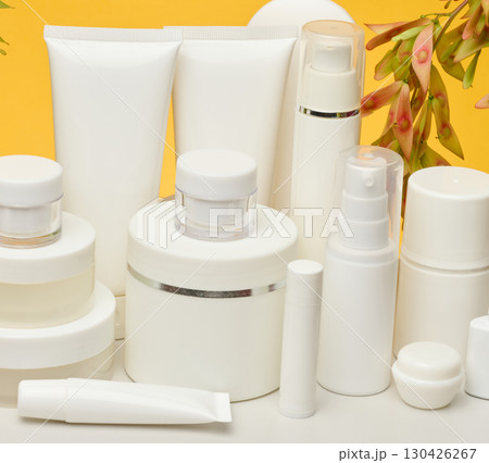 Set of white plastic cosmetic packaging without brand on yellow background. Container for beauty industry, skin care and advertising Set of white plastic cosmetic packaging without brand on yellow background. Container for beauty industry, skin care and advertising 130426267