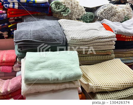 A collection of folded towels stacked on a store counter. Order, cleanliness, and textile display in a retail environment. A collection of folded towels stacked on a store counter. Order, cleanliness, and textile display in a retail environment. 130426374