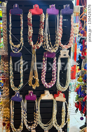 A display of shell and bead necklaces hanging on a stand. Jewelry, craftsmanship, and colorful summer fashion accessories. 130426376