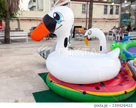 Inflatable swan float displayed on the street for sale. Summer fun, leisure, and water activity accessories. 130426422