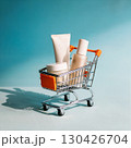 Minimalist skincare essentials in a miniature shopping cart on bright teal background with strong shadows 130426704
