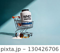 Whey protein container in shopping cart with spilled fish oil capsules and powder on pastel blue background, symbolizing fitness and nutrition 130426706