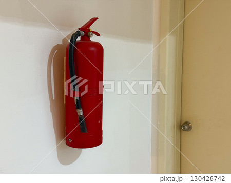 Red fire extinguisher mounted on a wall indoors. Safety, protection and emergency preparedness in a public or private space. Red fire extinguisher mounted on a wall indoors. Safety, protection and emergency preparedness in a public or private space. 130426742