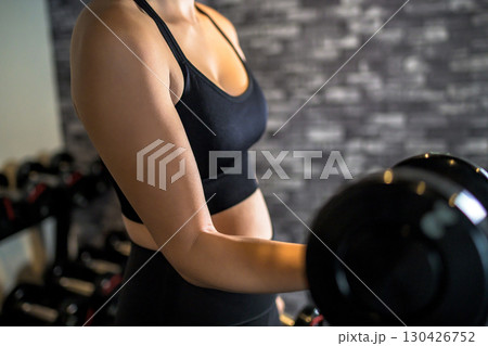 ダンベルを片手で持ち上げる女性 ジムで運動するかっこいい女性 上半身 筋トレ女子 顔無しパーツカット ダンベルを片手で持ち上げる女性 ジムで運動するかっこいい女性 上半身 筋トレ女子 顔無しパーツカット 130426752