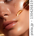 Close-up of luxury facial oil drops on smooth glowing skin with golden dropper for skincare and beauty treatment 130426819