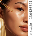 Glowing skin with drop of serum from golden dropper in close-up view representing healthy skincare and moisture 130426821