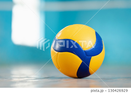 Volleyball blue and yellow ball on the floor in the gym. Concept of sport training, physical improvement, active way of life 130426929