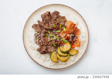 Korean beef bulgogi bowl dish with rice, roasted meat, kimchi and marinated cucumber on white background top view with chopsticks Korean beef bulgogi bowl dish with rice, roasted meat, kimchi and marinated cucumber on white background top view with chopsticks 130427430