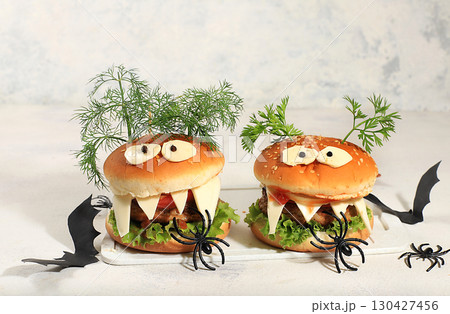 Halloween food concept. Scary hamburgers with fresh parsley leaves, tomatoes, cream cheese, onion and cutlet on a concrete background, the idea of cooking, food delivery, 130427456