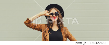 Fashion portrait of beautiful happy young woman, stylish girl smiling in black round hat posing Fashion portrait of beautiful happy young woman, stylish girl smiling in black round hat posing 130427686