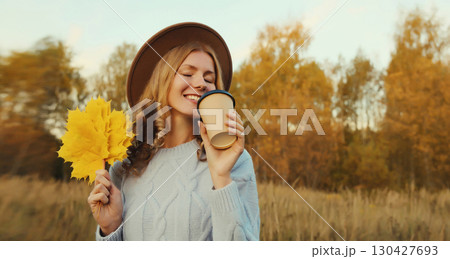 Happy young woman with yellow leaves, girl smiling holding cup of coffee drink in autumn park Happy young woman with yellow leaves, girl smiling holding cup of coffee drink in autumn park 130427693
