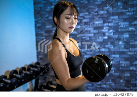 ダンベルを持ち上げる女性 ジムで運動するかっこいい女性 ダンベルカール 筋トレ女子 ダンベルを持ち上げる女性 ジムで運動するかっこいい女性 ダンベルカール 筋トレ女子 130427879