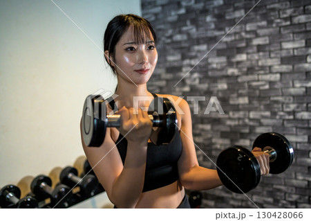 ダンベルで腕を鍛える女性　ジムで運動するかっこいい女性　ダンベルカール　筋トレ女子　 130428066