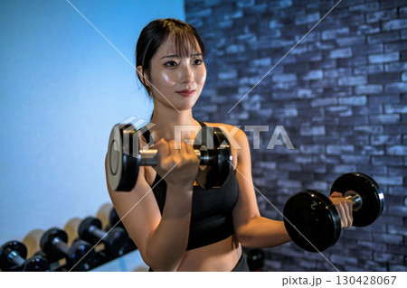 ダンベルで腕を鍛える女性　ジムで運動するかっこいい女性　ダンベルカール　筋トレ女子　 130428067