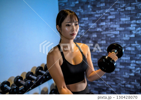 ダンベルで腕を鍛える女性　ジムで運動するかっこいい女性　ダンベルカール　筋トレ女子　 130428070