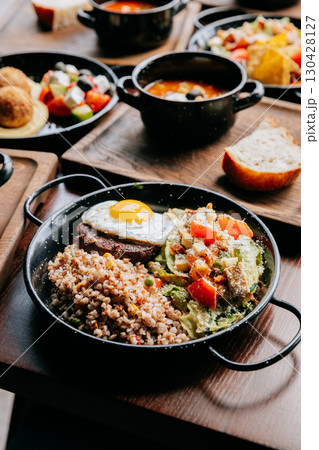 Nutritious lunch with buckwheat, fried egg, grilled patty and Caesar salad on wooden table 130428127