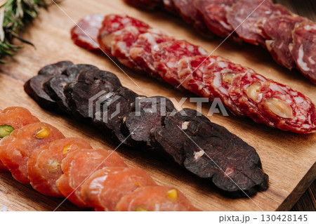 Close-up of gourmet sliced sausage with nuts on wooden board, traditional cured meat snack Close-up of gourmet sliced sausage with nuts on wooden board, traditional cured meat snack 130428145