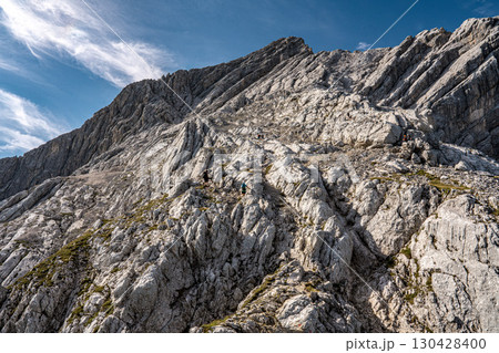 Rocky Section Of The Via Ferrata Alpspitze In The Bavarian Alps: Dramatic Cliffs And Mountain Peaks Under Scenic Blue Sky Rocky Section Of The Via Ferrata Alpspitze In The Bavarian Alps: Dramatic Cliffs And Mountain Peaks Under Scenic Blue Sky 130428400