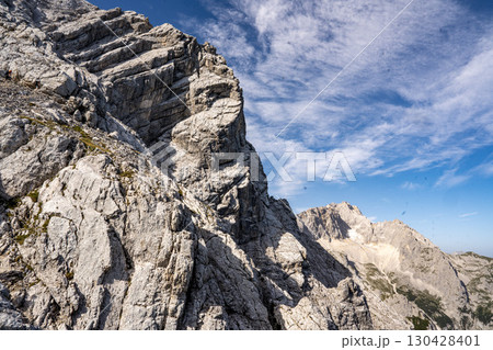 Rocky Section Of The Via Ferrata Alpspitze In The Bavarian Alps: Dramatic Cliffs And Mountain Peaks Under Scenic Blue Sky Rocky Section Of The Via Ferrata Alpspitze In The Bavarian Alps: Dramatic Cliffs And Mountain Peaks Under Scenic Blue Sky 130428401