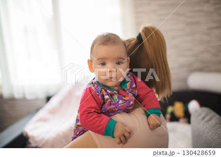 Caring mother holding newborn baby girl at home 130428659
