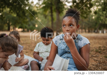 Children eating snacks and watching a movie in the park 130428807