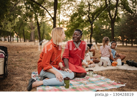 Mothers enjoying a picnic in the park while their children are playing Mothers enjoying a picnic in the park while their children are playing 130428819