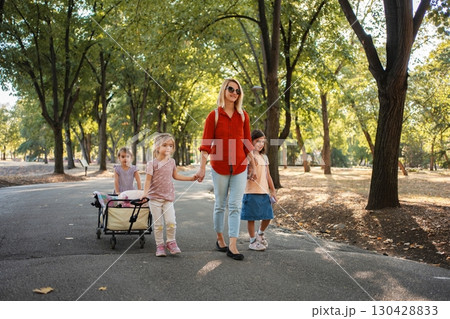 Mother and daughters walking in the park, pulling a wagon 130428833