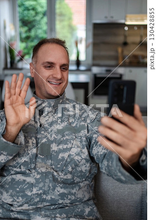 Happy soldier making a video call with family from home 130428855