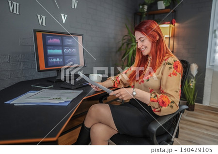 Businesswoman analyzing financial reports and working on computer in office 130429105