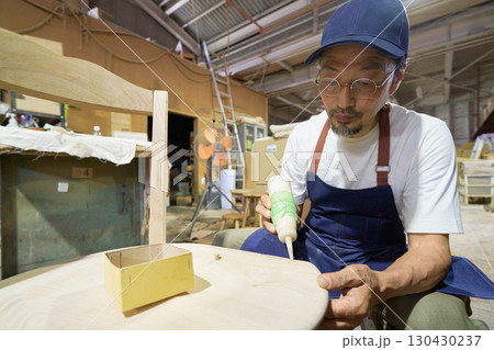 家具製作の組み立て工程で接着作業を行う職人 130430237