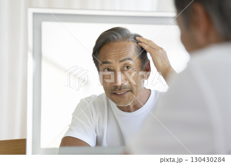 鏡を見て生え際を気にする60代の男性 鏡を見て生え際を気にする60代の男性 130430284