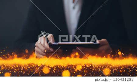 person in suit uses tablet with stylus, surrounded by glowing orange particles, creating futuristic and dynamic atmosphere 130431285