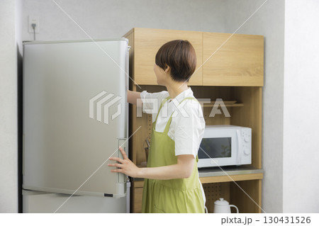 冷蔵庫を開けるエプロン姿の女性　　 130431526