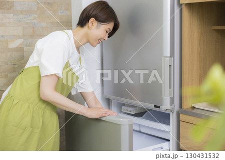 冷蔵庫を開けるエプロン姿の女性　　 130431532