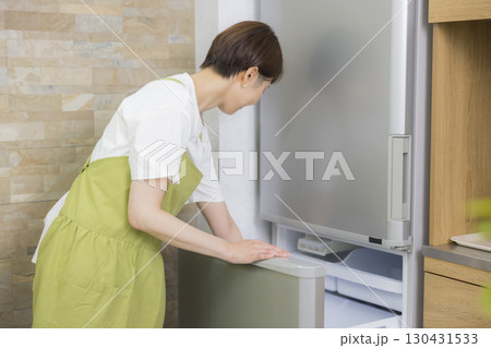 冷蔵庫を開けるエプロン姿の女性 冷蔵庫を開けるエプロン姿の女性 130431533