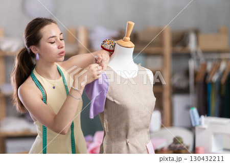 Woman seamstress adjusts clothes on mannequin Woman seamstress adjusts clothes on mannequin 130432211