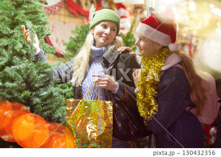 Happy mother and teenage daughter looking for Christmas tree on outdoor market 130432356