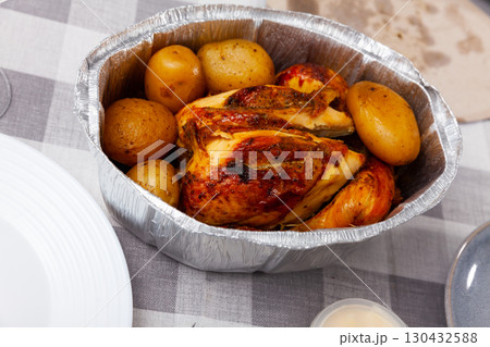 on table in baking dish is ready-to-eat fried chicken with potatoes in skin 130432588