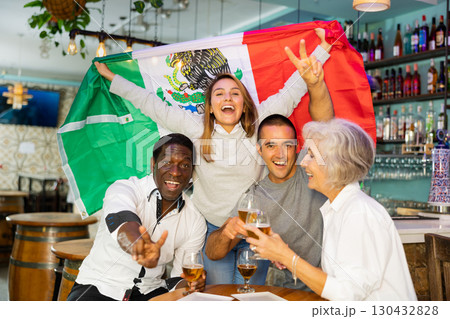 Excited multiracial soccer fans with flag of Mexico celebrating victory with pint of beer in the pub Excited multiracial soccer fans with flag of Mexico celebrating victory with pint of beer in the pub 130432828
