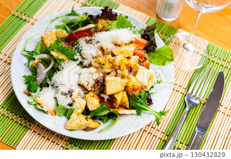 Caesar salad with chicken pieces, croutons, tomatoes, lettuce and parmesan cheese 130432829