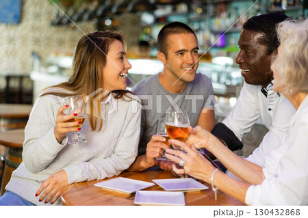 Cheerful international friends different ages enjoying pinchos and beer in the evening pub 130432868