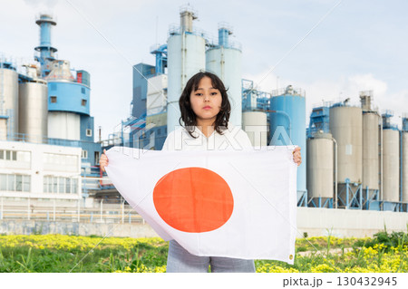 Worried asian girl with flag of japan standing in front of industrial scenery Worried asian girl with flag of japan standing in front of industrial scenery 130432945