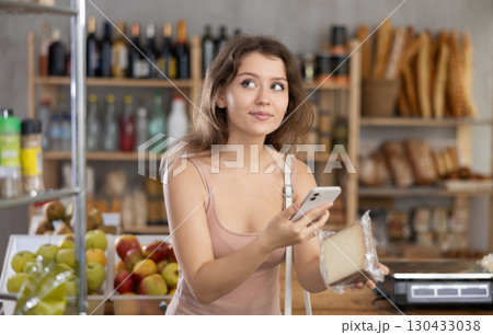 Woman scanning QR code on cheese package for info in grocery Woman scanning QR code on cheese package for info in grocery 130433038